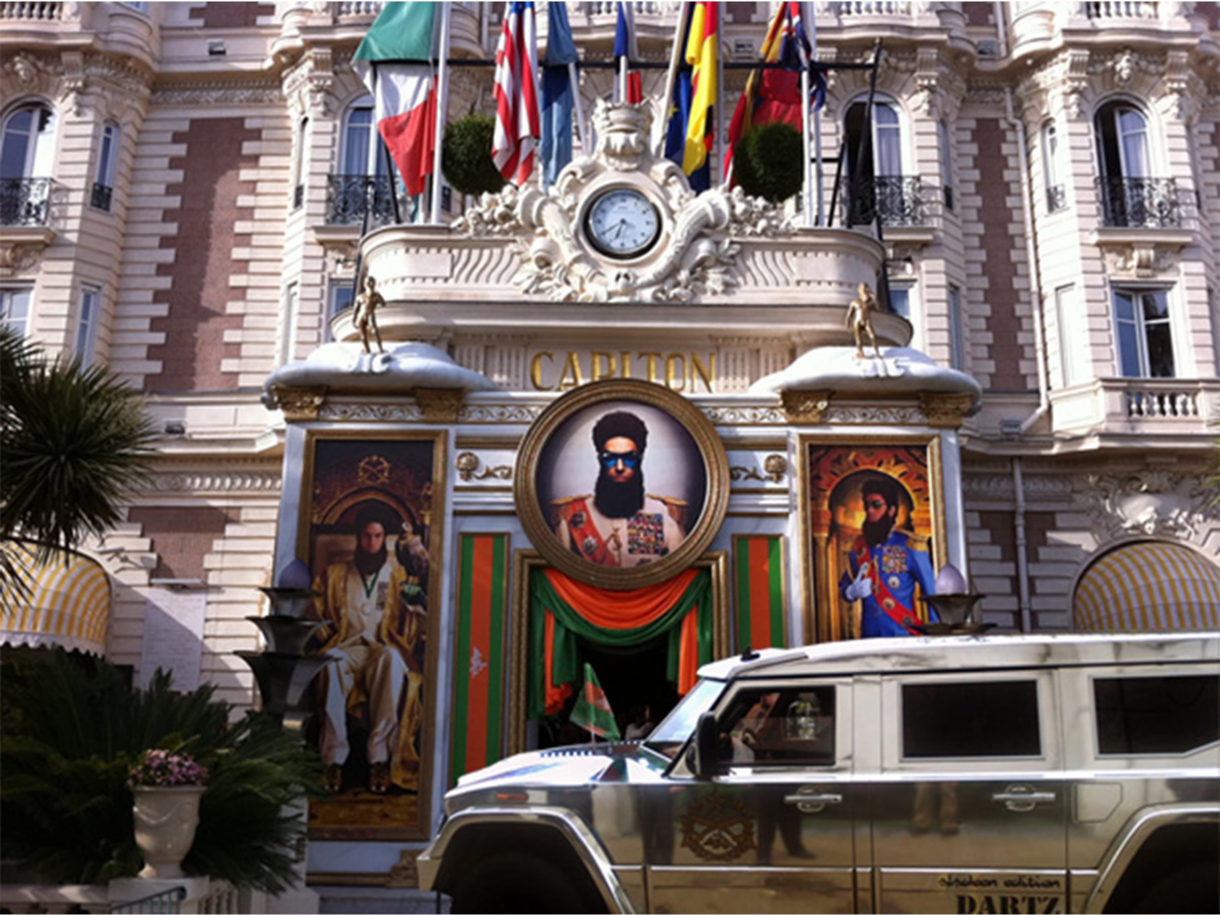 Hotel façade dressed for The Dictator, with a gold DARTZ Prombron’ parked outside
