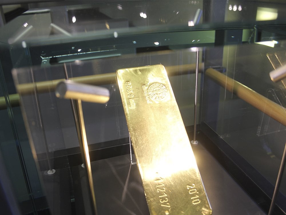Gold ingot on a stand inside a glass display