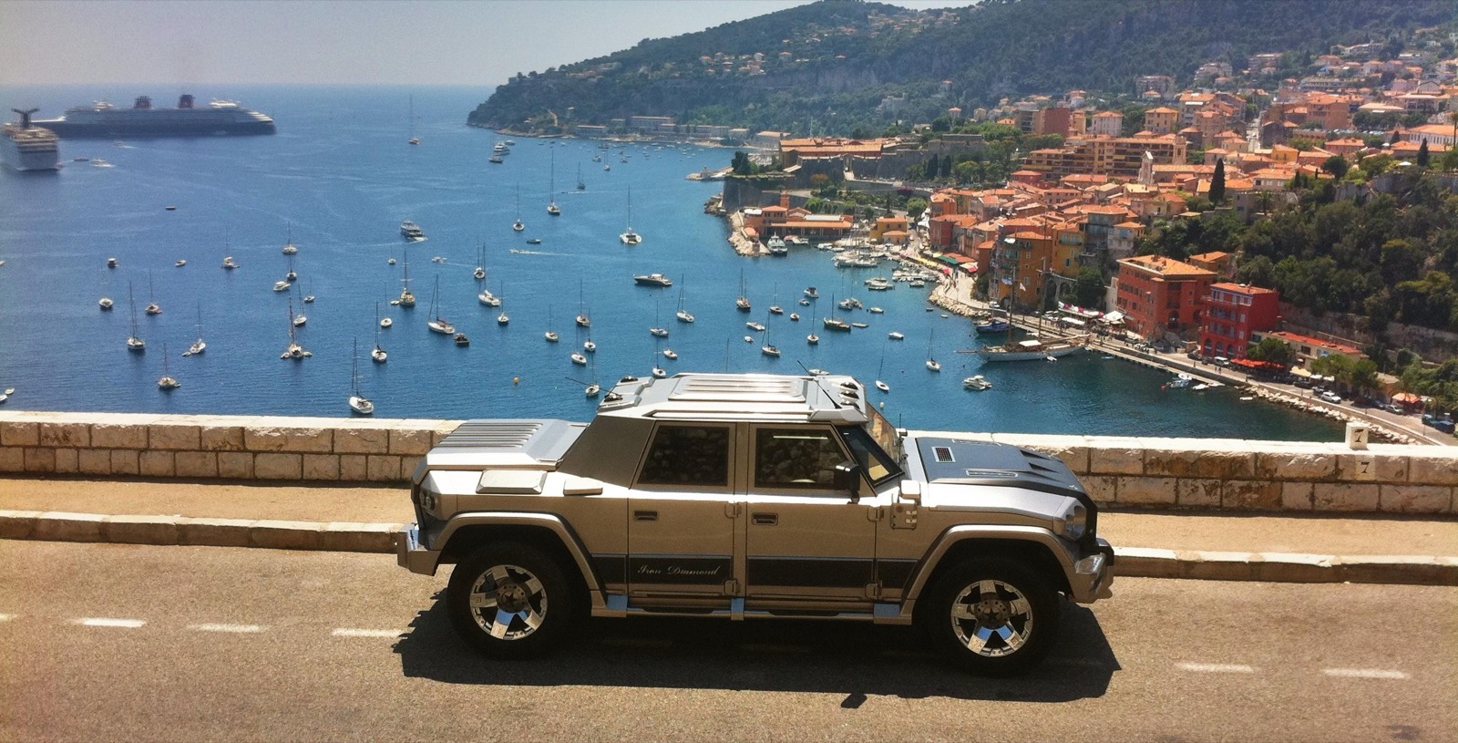 A DARTZ Prombron’ Iron Diamond, its name in script on the door, on a corniche road above a Riviera harbour